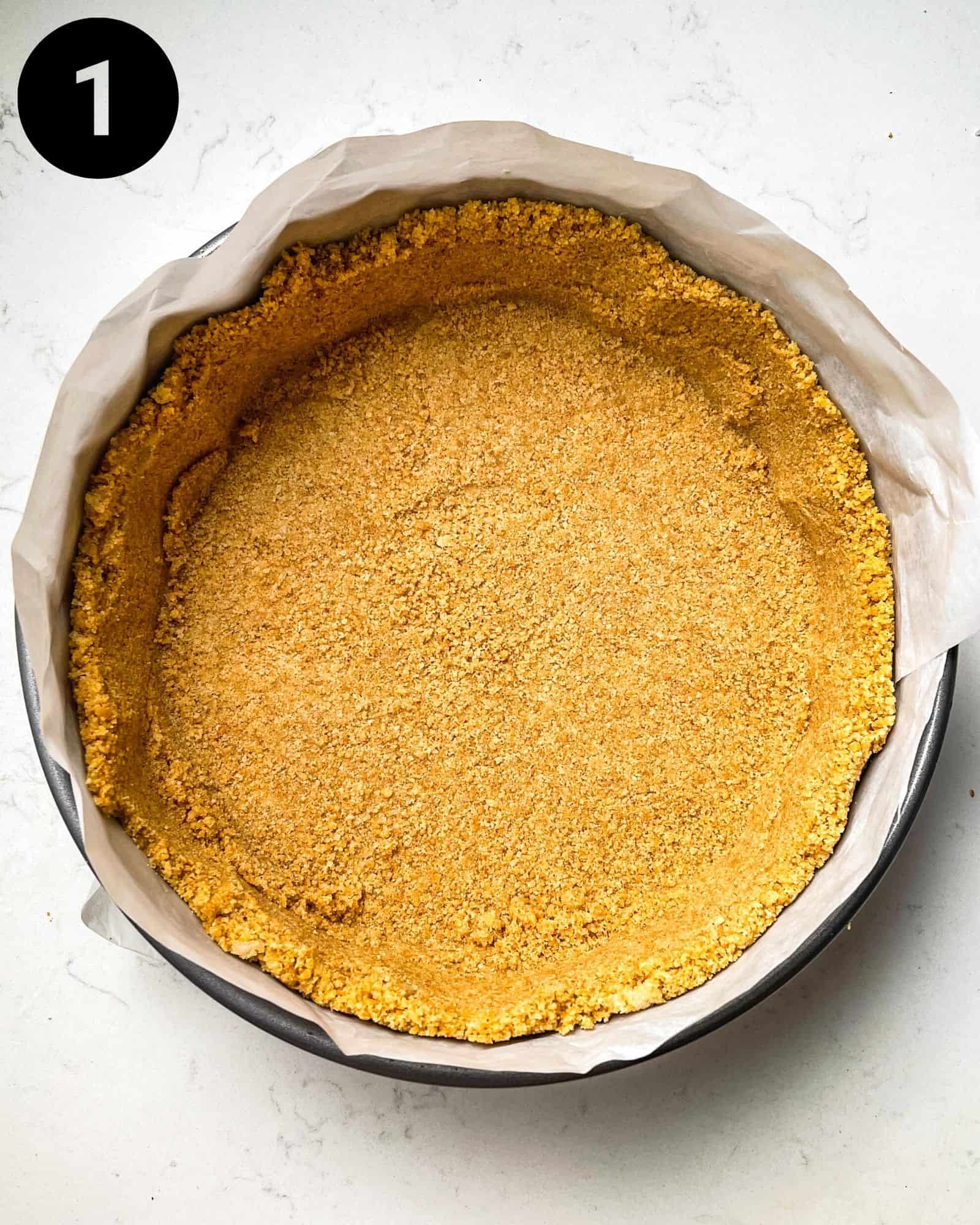 graham cracker crust in a springform pan lined with parchment paper.
