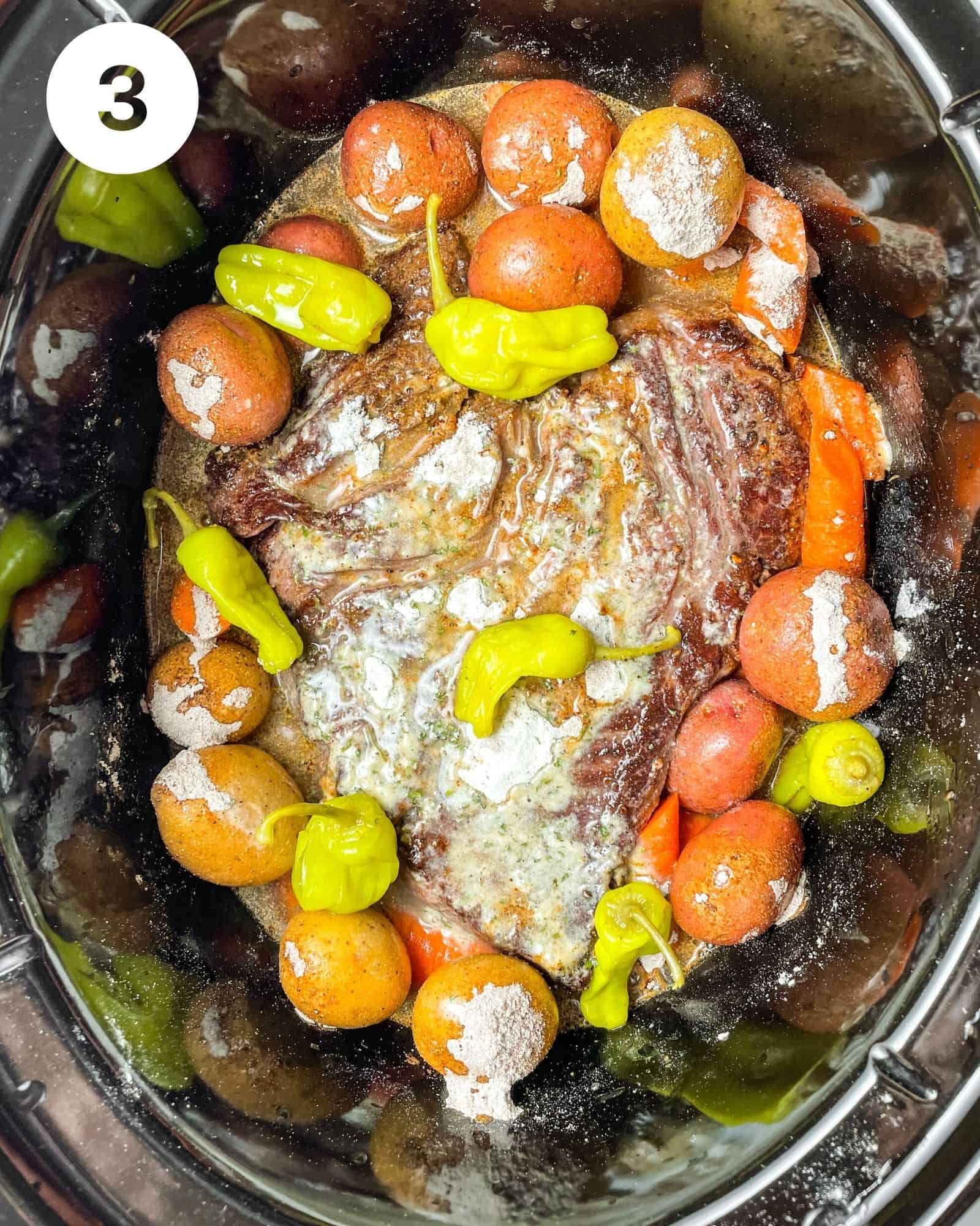 mississippi pot roast in a slow cooker with potatoes, carrots, pepperoncini peppers, beef broth, seasoning packets, and butter.