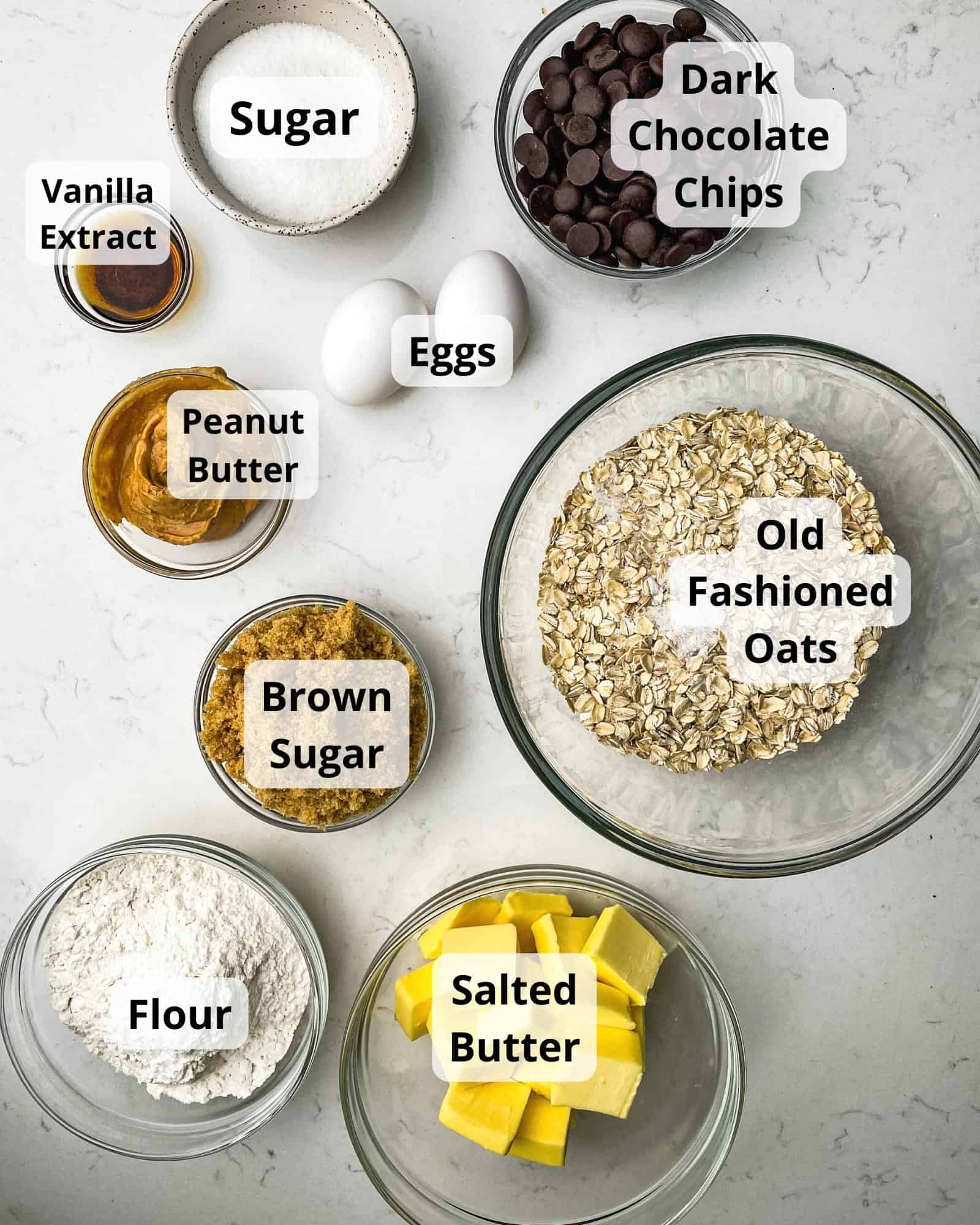 ingredients to make chocolate peanut butter oatmeal bars - oats, flour, baking soda, salt, butter, sugar, brown sugar, vanilla extract, dark chocolate chips, eggs, and peanut butter.