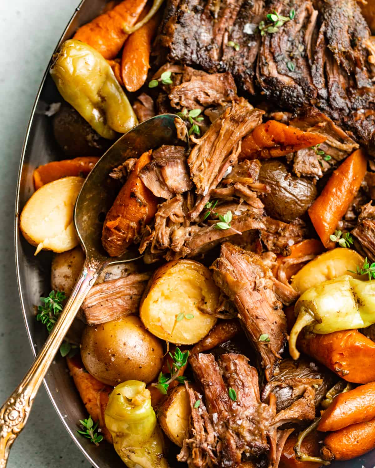 Mississippi Pot Roast in a serving dish with potatoes and carrots.
