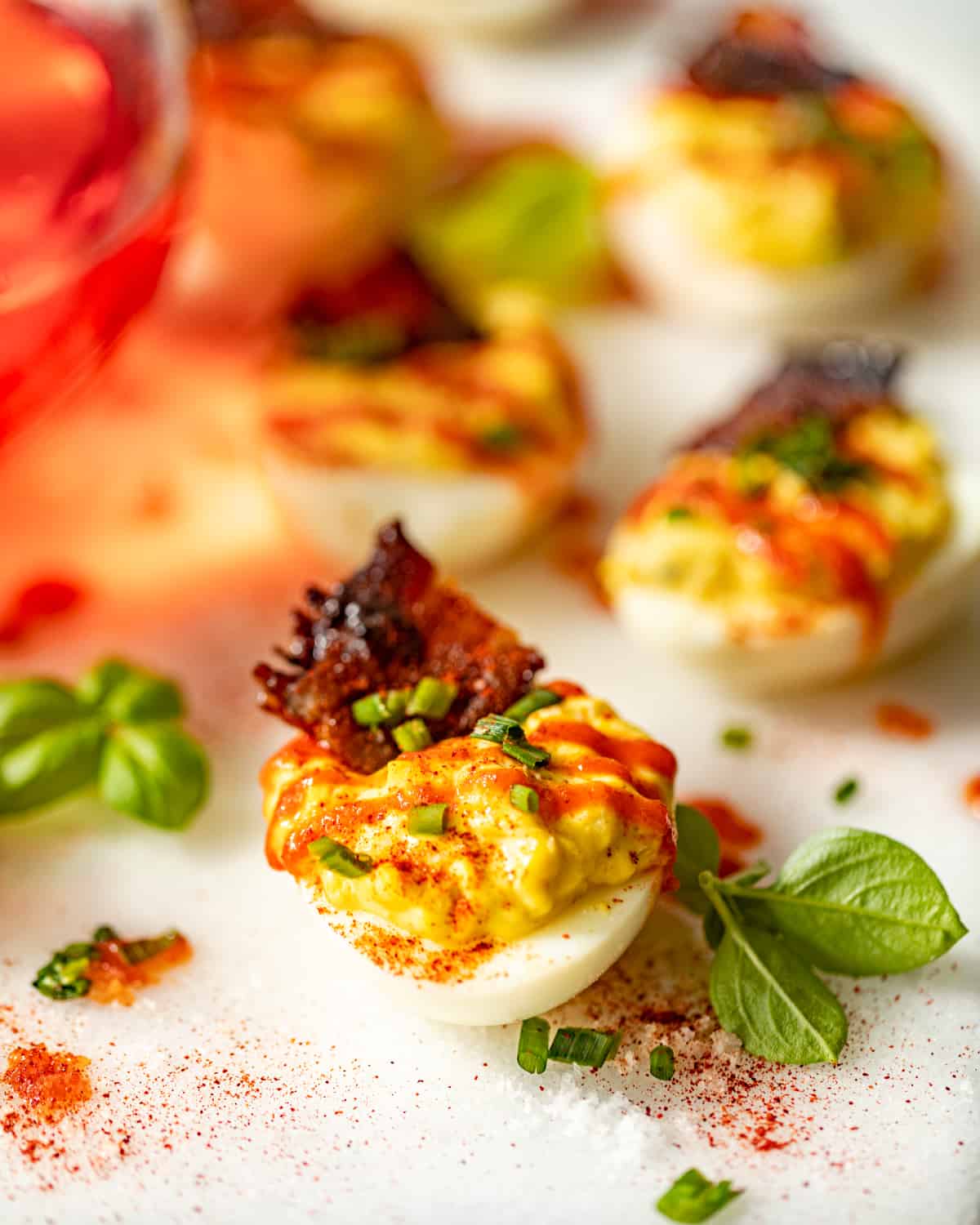 a deviled egg on a tray with bacon and smoked paprika on top.