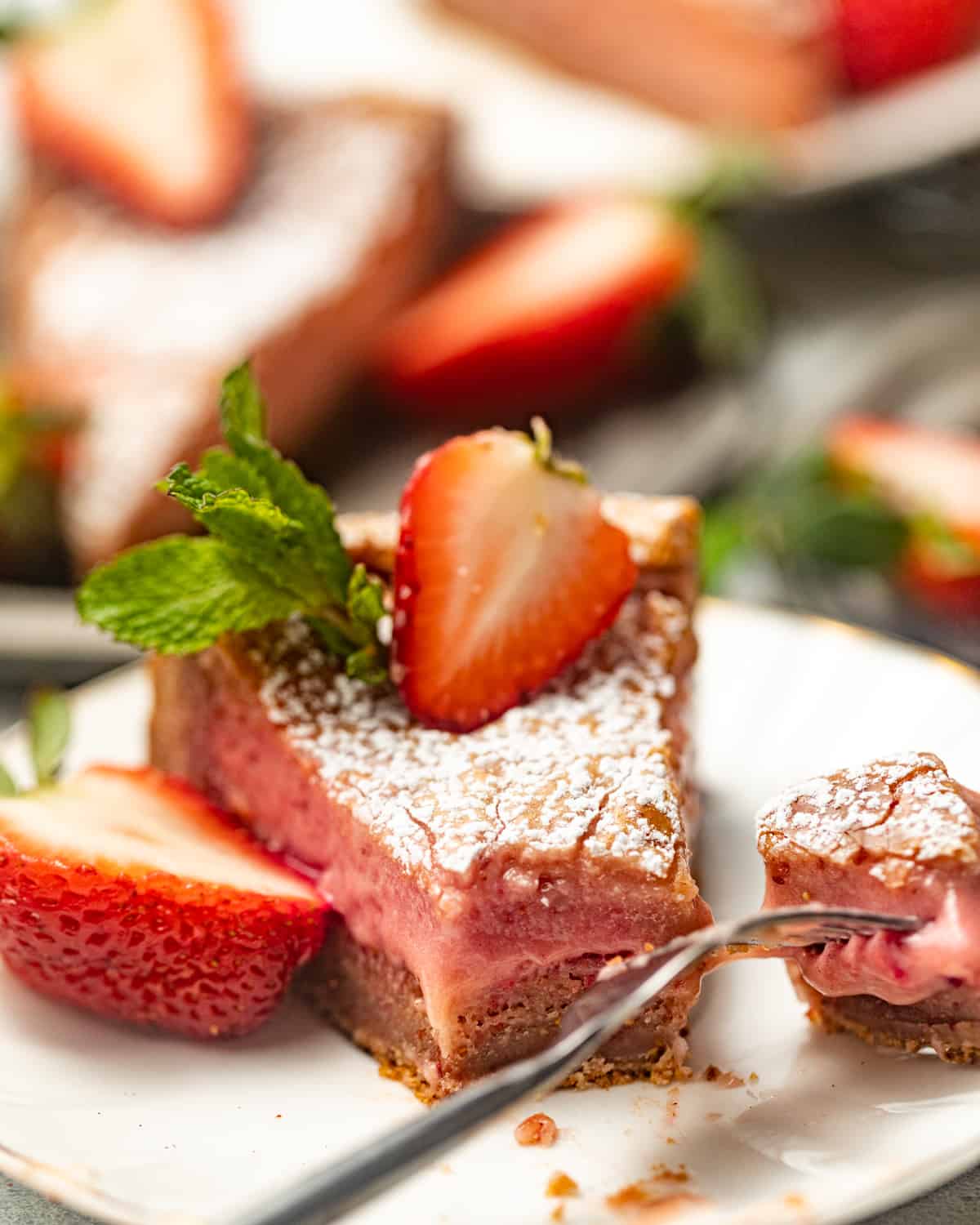 sliced strawberry butter cake on a white plate with a fork and a strawberry on top.