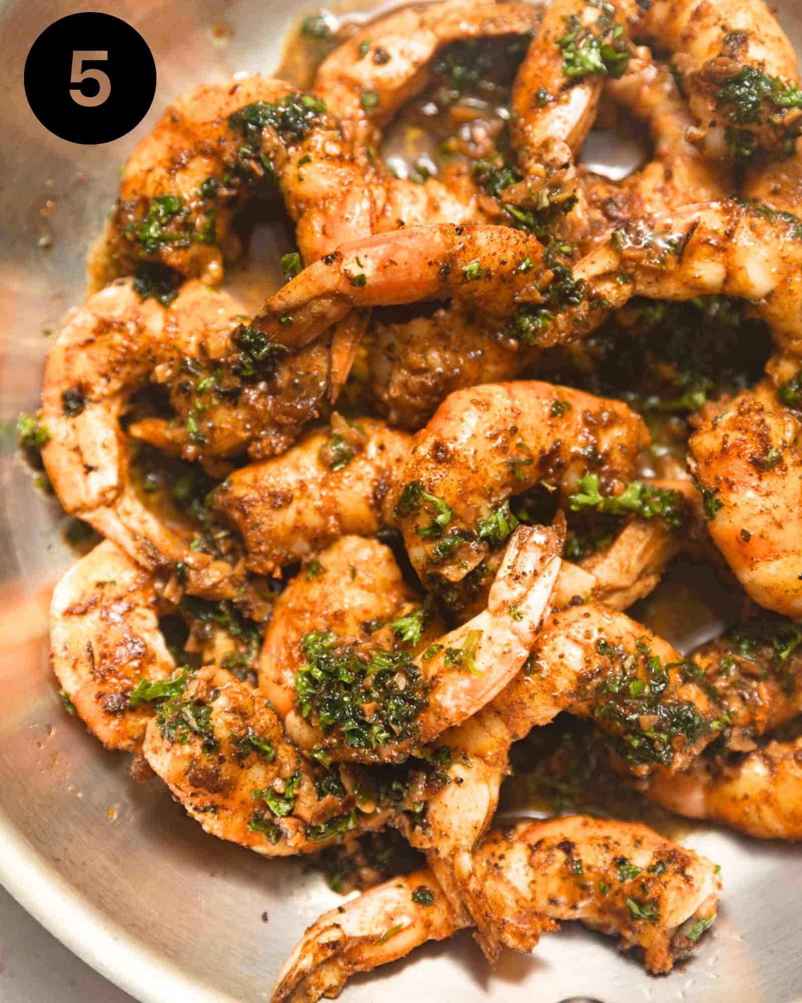 pan seared shrimp in a stainless steel pan coated with garlic butter sauce.