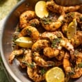 pan seared shrimp in a skillet with lemons and parsely.
