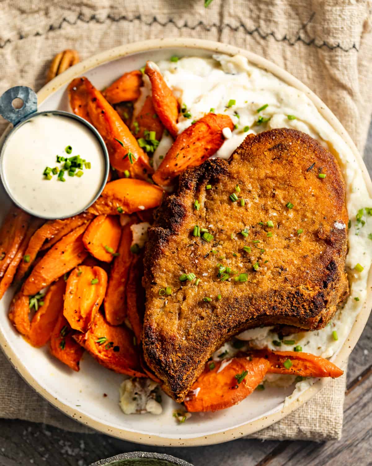 pork chops on a plate with mashed potatoes and honey glazed carrots.