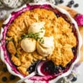 blueberry cobbler in a pie pan topped with vanilla ice cream.