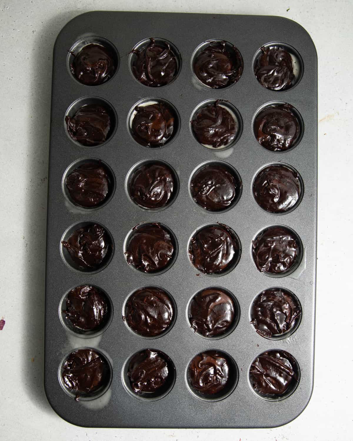 A mini muffin tin filled with brownie batter.