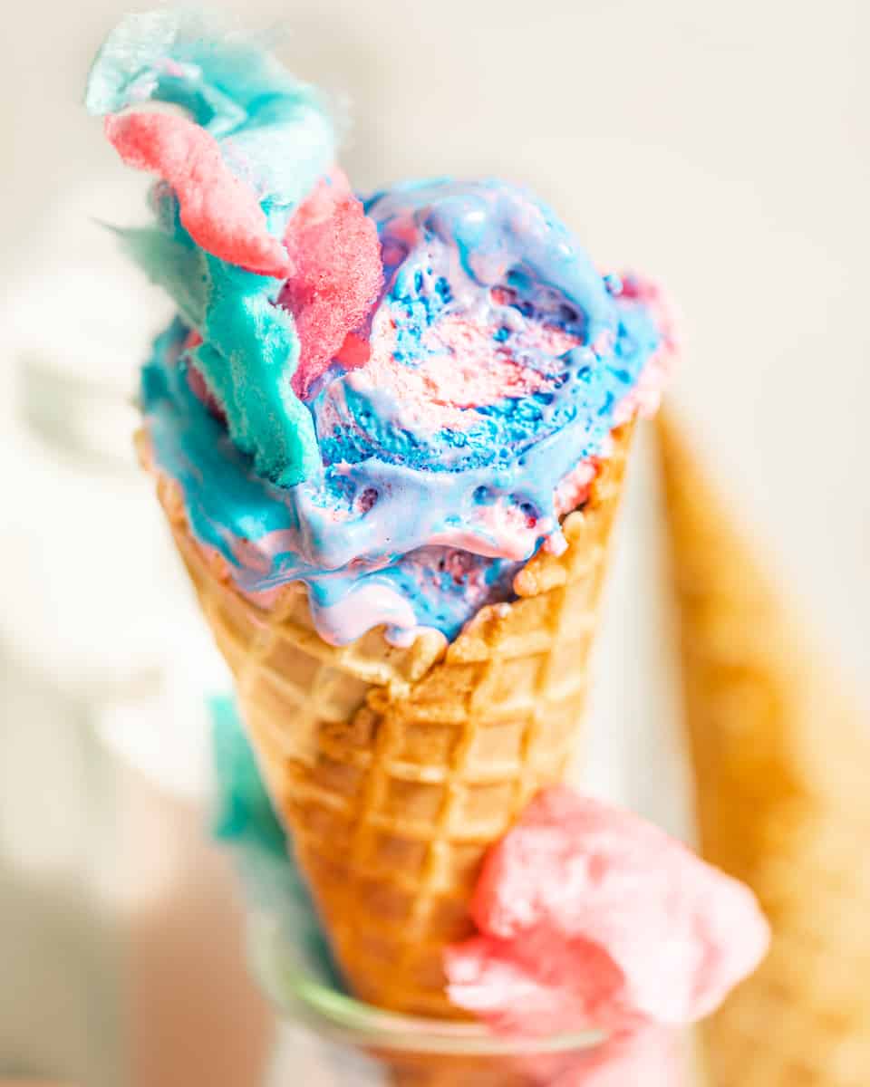 cotton candy ice cream in a waffle cone with real cotton candy on top.