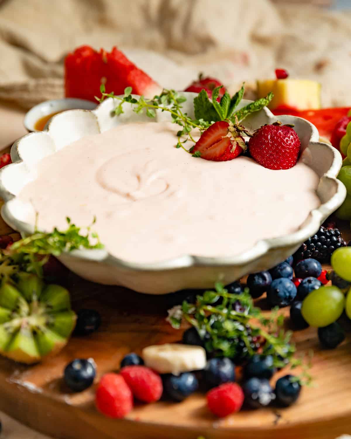 a fruit board with fruit dip in a bowl.