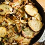 Fried sliced potatoes and onions in a cast iron skillet.