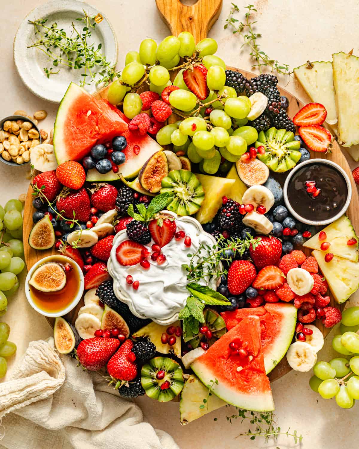 a fruit charcuterie board with a variety of fruits and dips on a wooden tray.