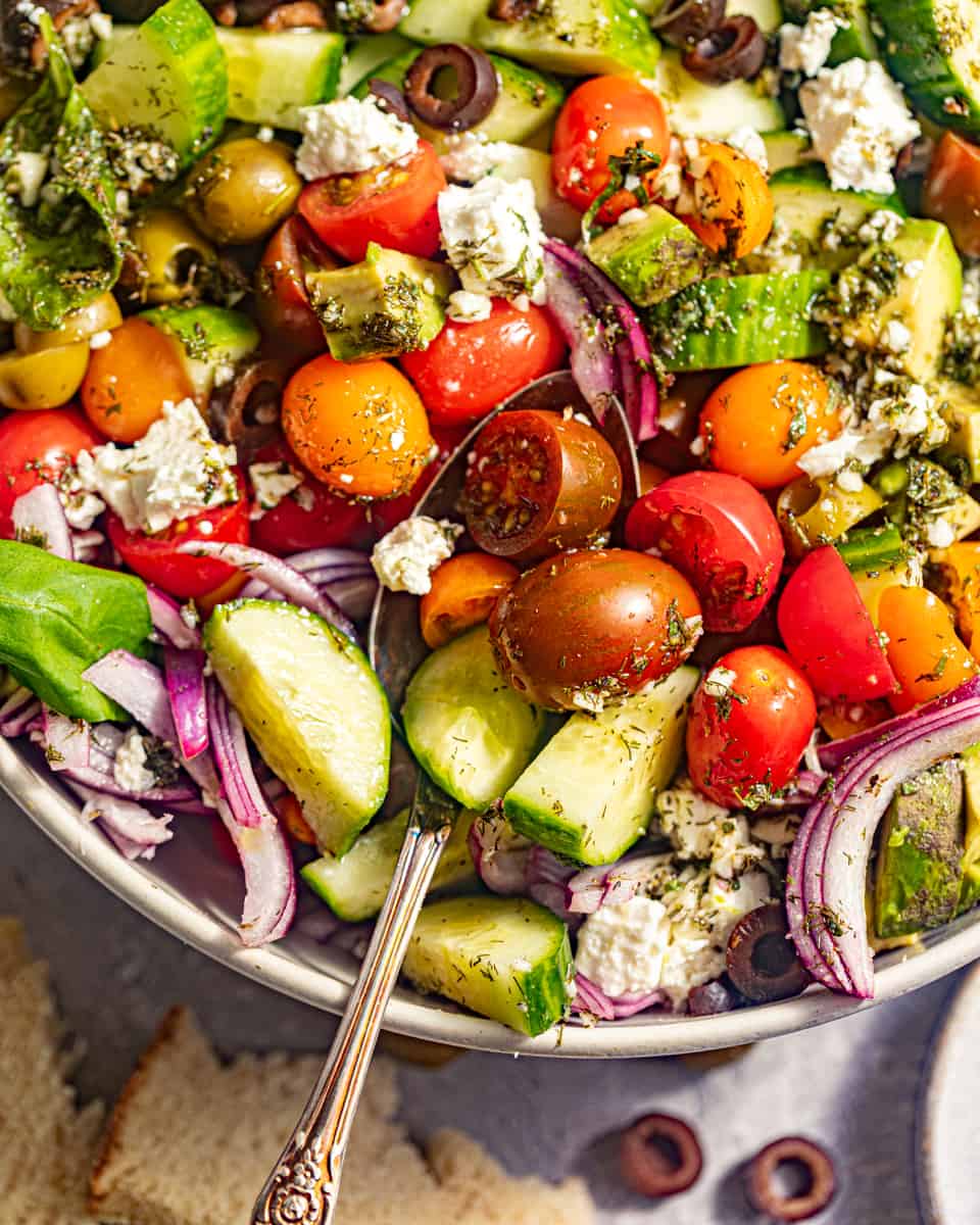 up close photo of greek salad in a bowl with a spoon.
