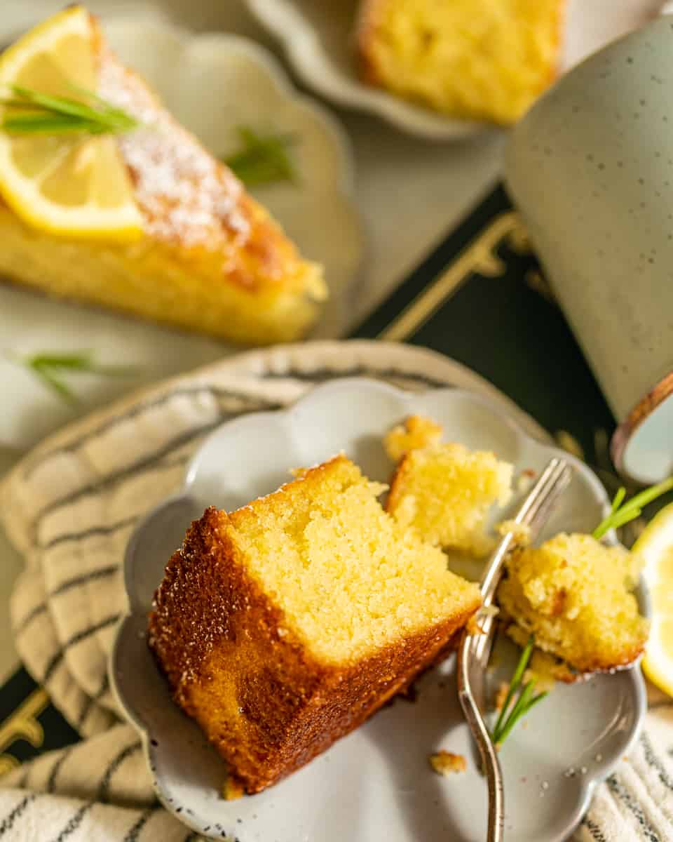 a slice of olive oil cake on a small plate with a fork.
