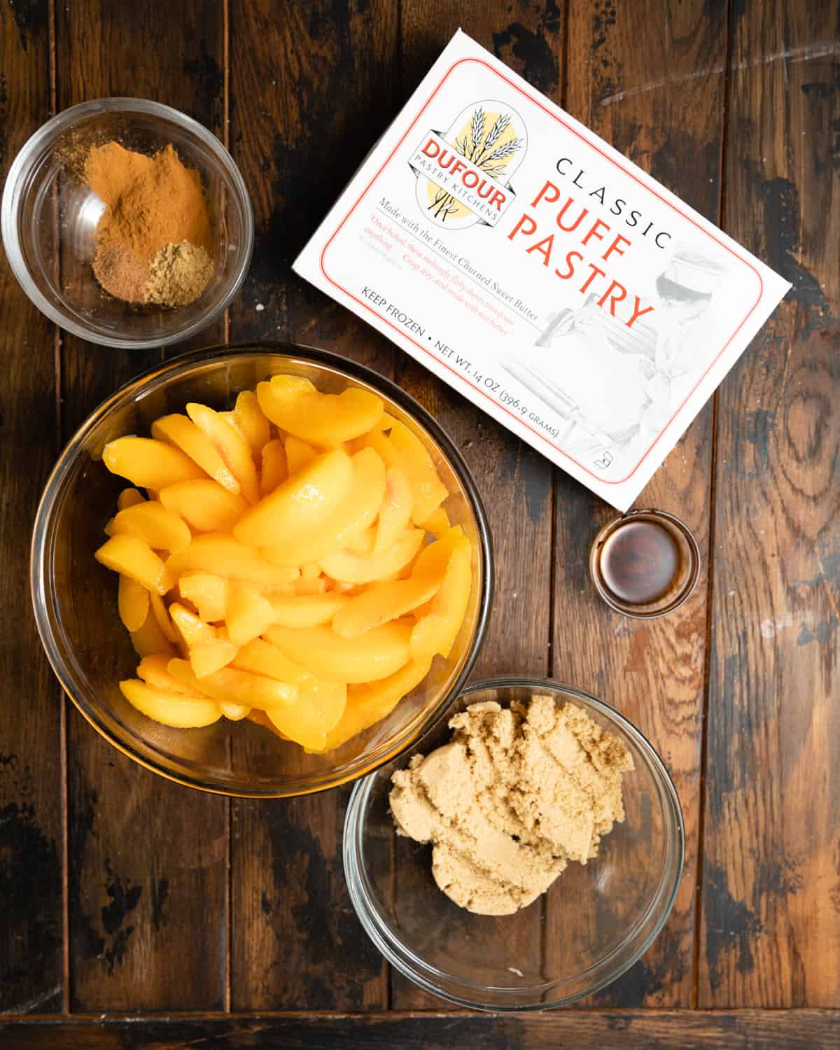 Ingredients to make a rustic peach galette on a wooden table.