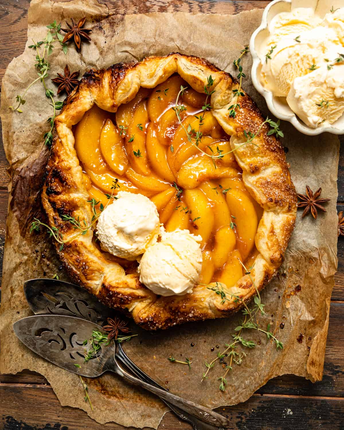 Rustic peach galette with two scoops of vanilla ice cream on top.
