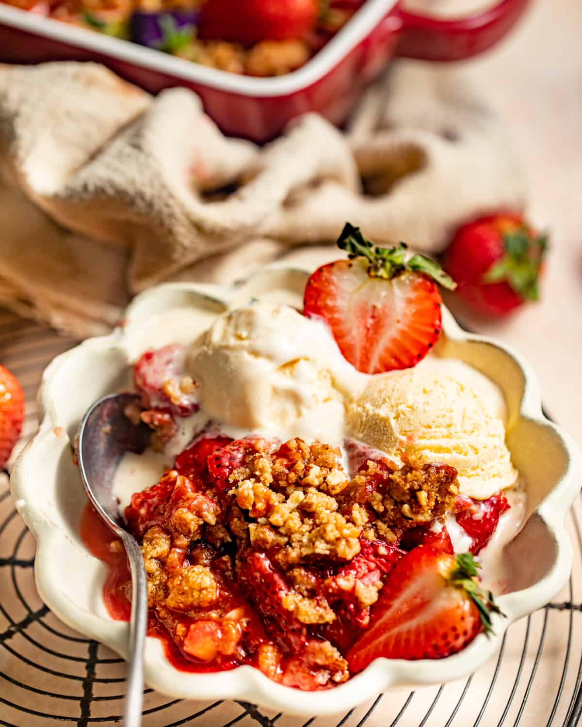 strawberry crumble in a bowl with a scoop of ice cream and fresh strawberries.