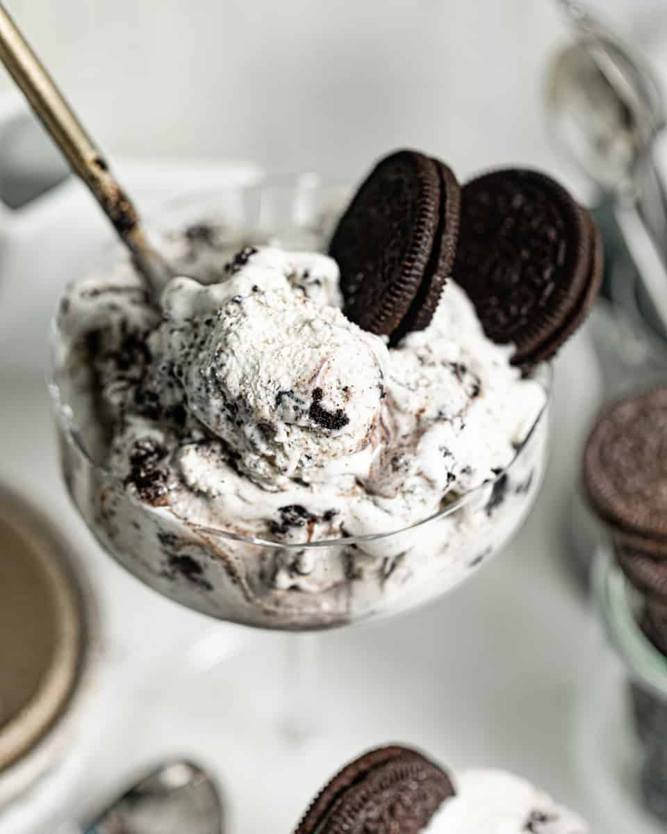 up close photo of oreo ice cream in a glass with a spoon.