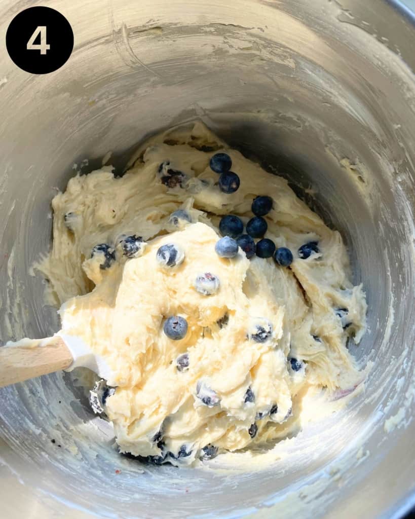 cake batter in a mixing bowl with fresh blueberries.