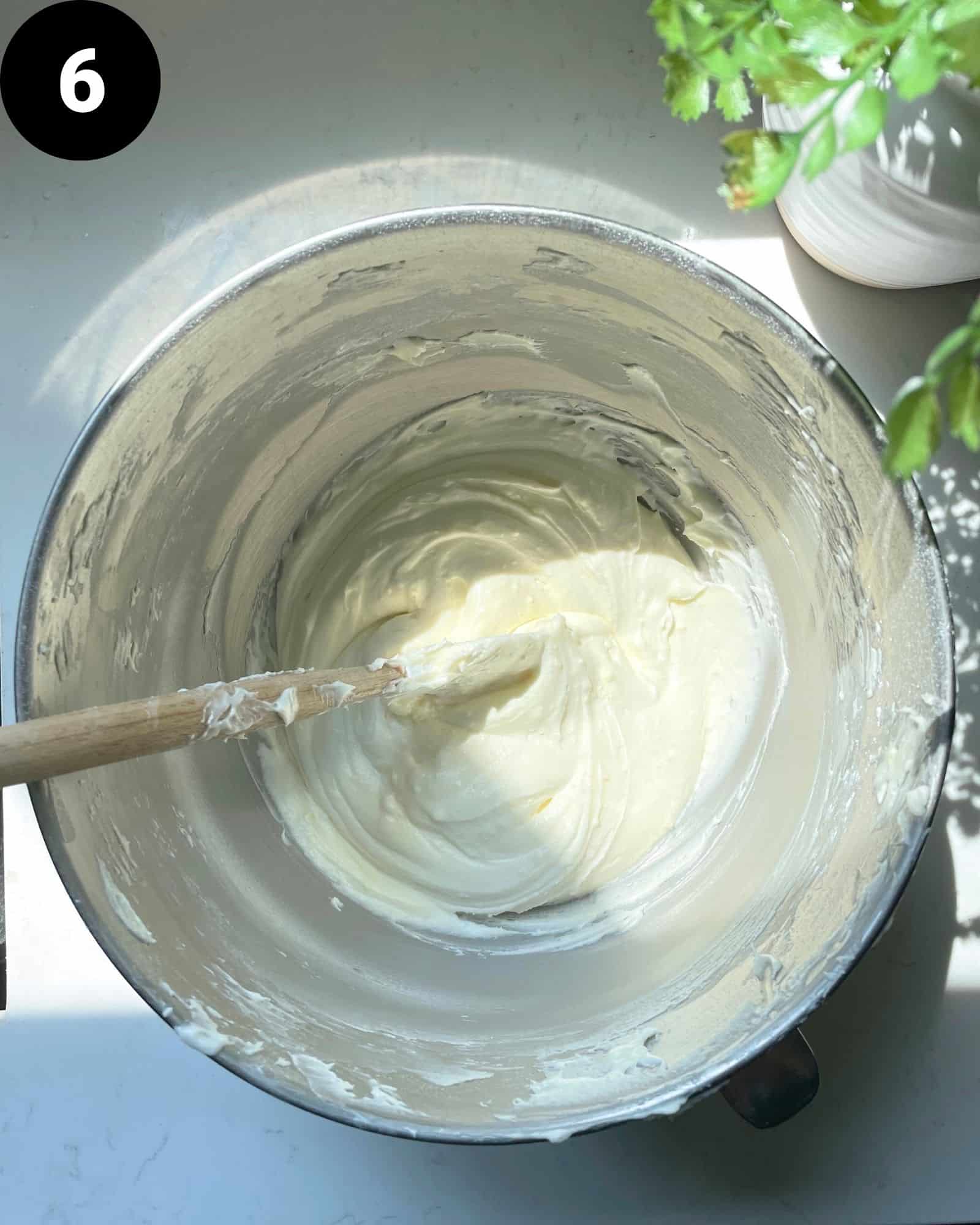 lemon cream cheese frosting in a mixing bowl with a rubber spatula.