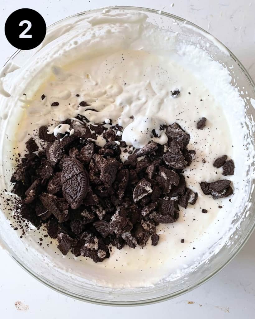 Crushed oreo cookies in a bowl with vanilla ice cream mixture.