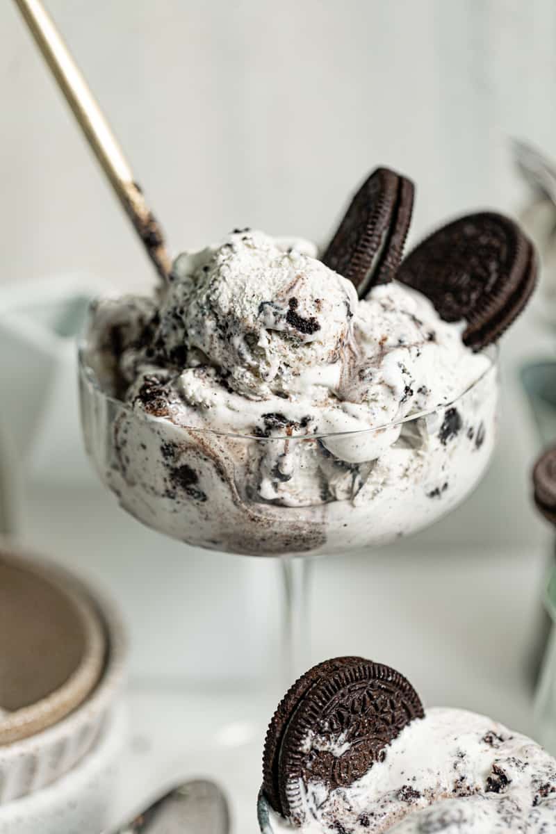 up close photo of oreo in a cup with oreo cookies on top and a spoon inserted into the ice cream.