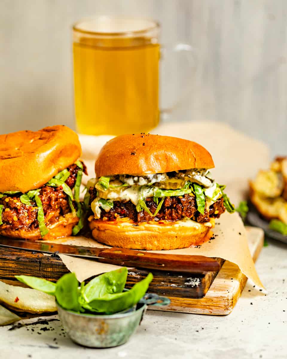 two fried chicken sandwiches on a serving board with a mug behind them.