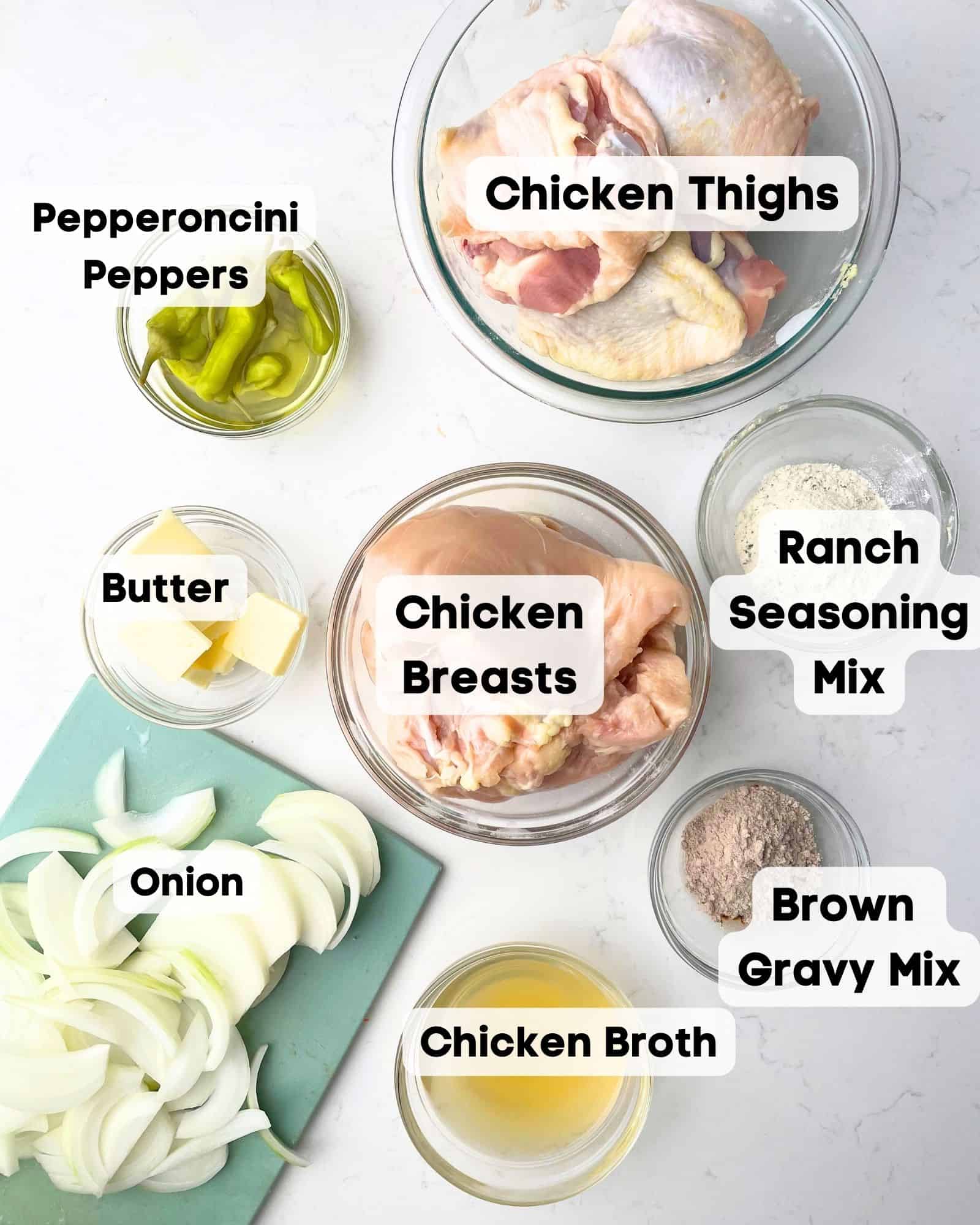 ingredients to make mississippi chicken - chicken, onions, pepperoncini peppers, pepperoncini juice, chicken broth, ranch seasoning mix, brown gravy mix, and butter.