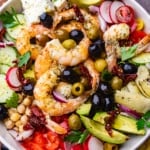 Mediterranean Shrimp Salad in a bowl atop a cutting board.