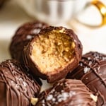 Peanut butter truffles in a pile with one bitten into.
