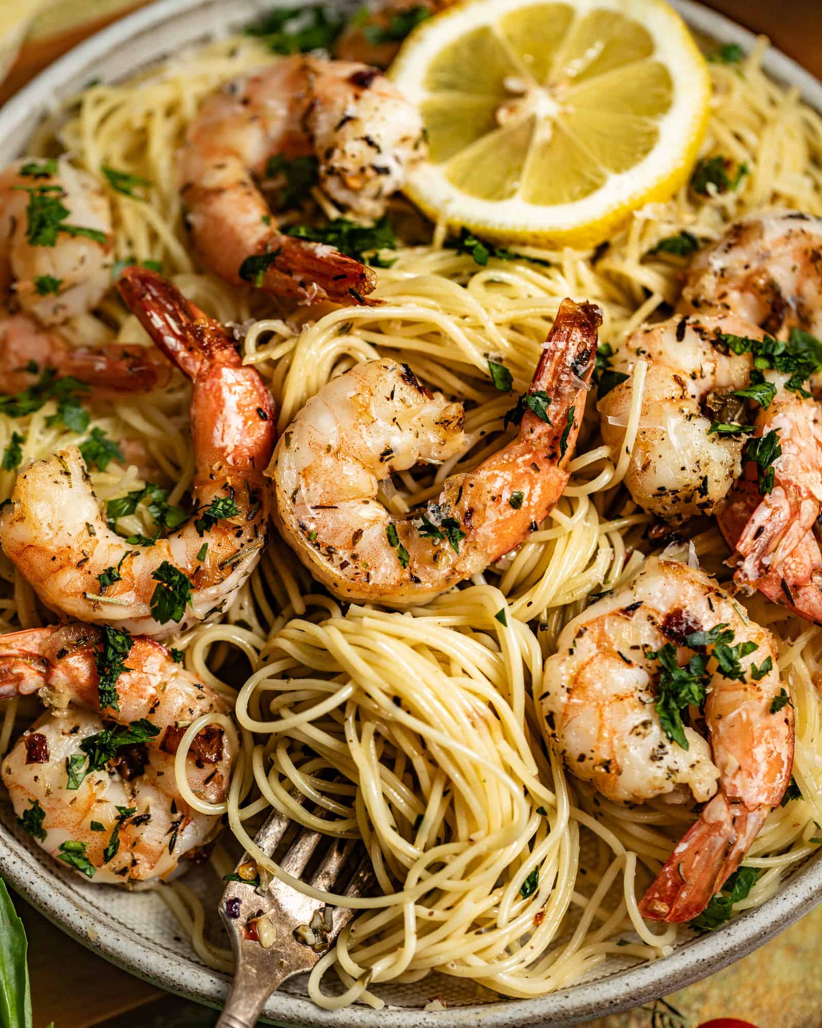 Shrimp scampi with lemon wedges over pasta and fresh parsley.