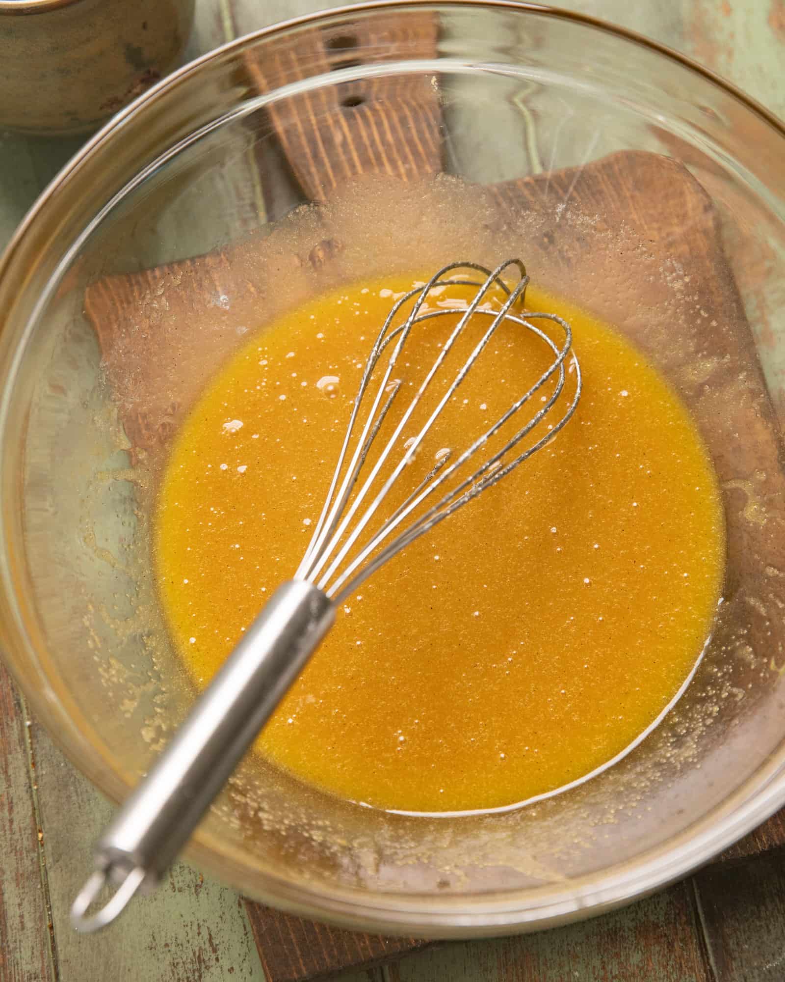 honey, butter, sugar, and brown sugar whisked together in a glass mixing bowl.