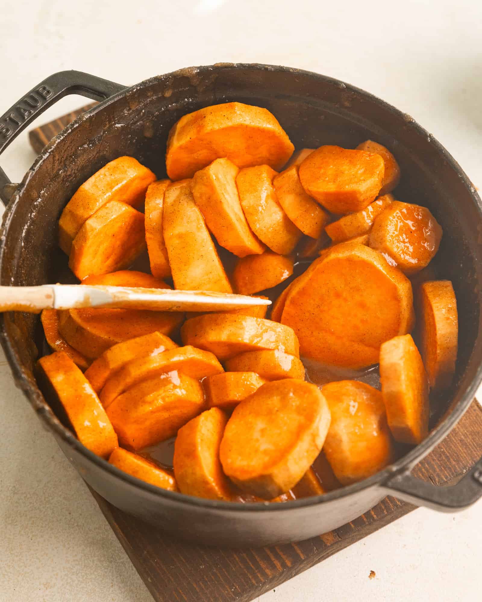 sliced sweet potatoes in a large pot covered in brown sugar syrup, spices, and butter