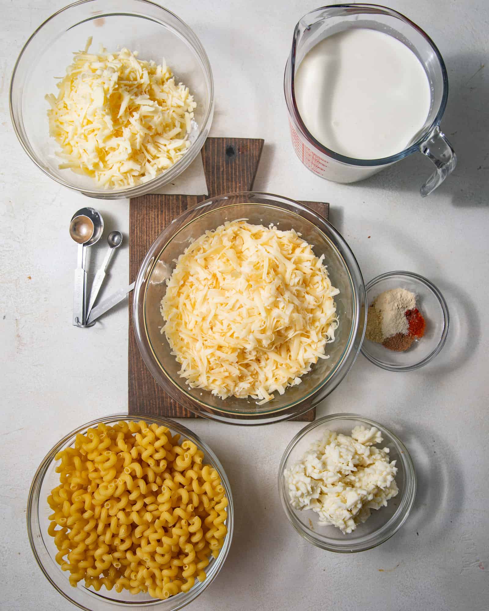 ingredients to make smoked gouda mac and cheese - heavy cream, milk, spices, mozzarella, cheddar, smoked gouda, flour, and pasta.