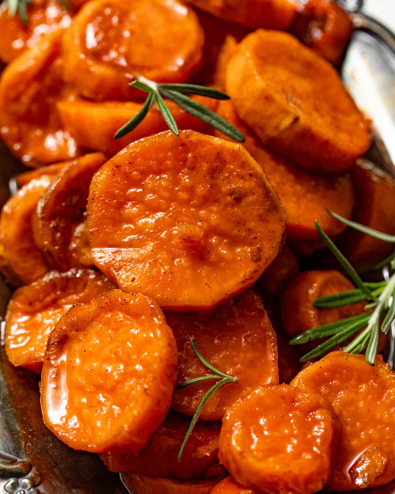 sliced sweet potatoes on a serving tray covered in syrup