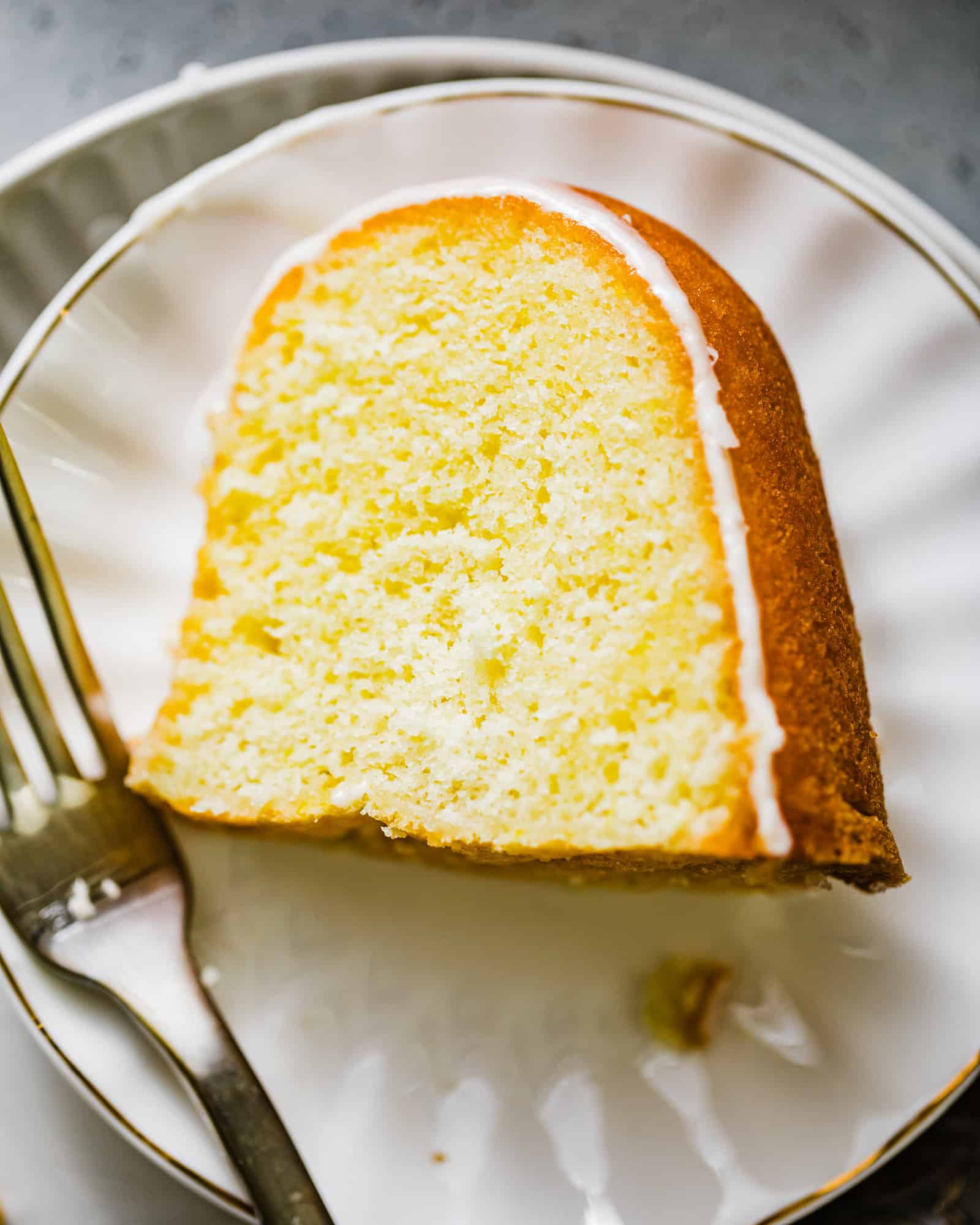 a slice of lemon pound cake on a plate with a fork.