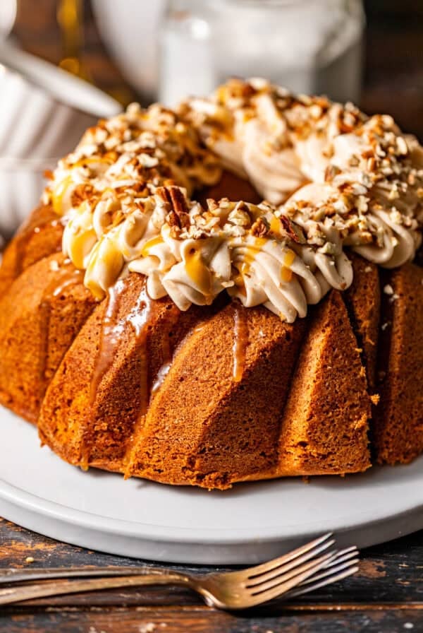 sweet potato pound cake on a serving plate topped with buttermilk syrup and cream cheese frosting.