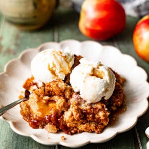apple cobbler on a plate with ice cream and a spoon.