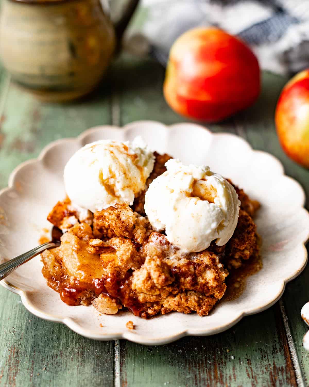 apple cobbler on a plate with ice cream and a spoon. 
