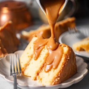 sliced caramel cake on a plate with caramel poured on top.