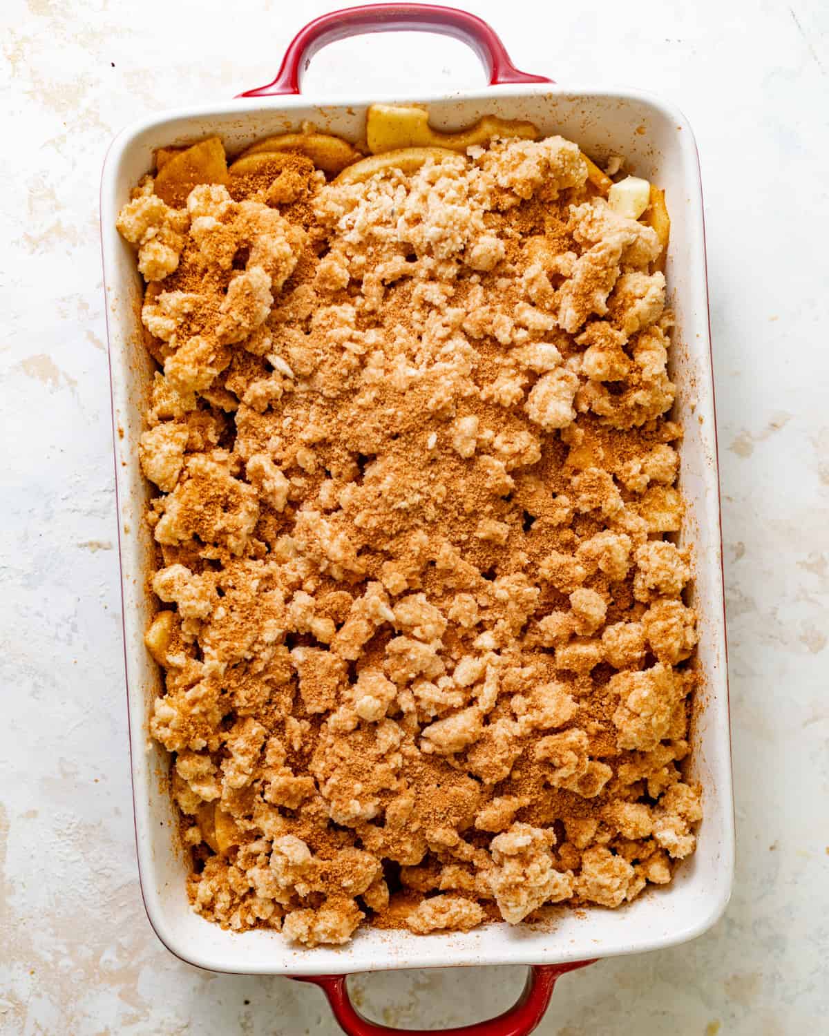 apple cobbler recipe assembled in a baking dish with cinnamon sugar sprinkled on top.
