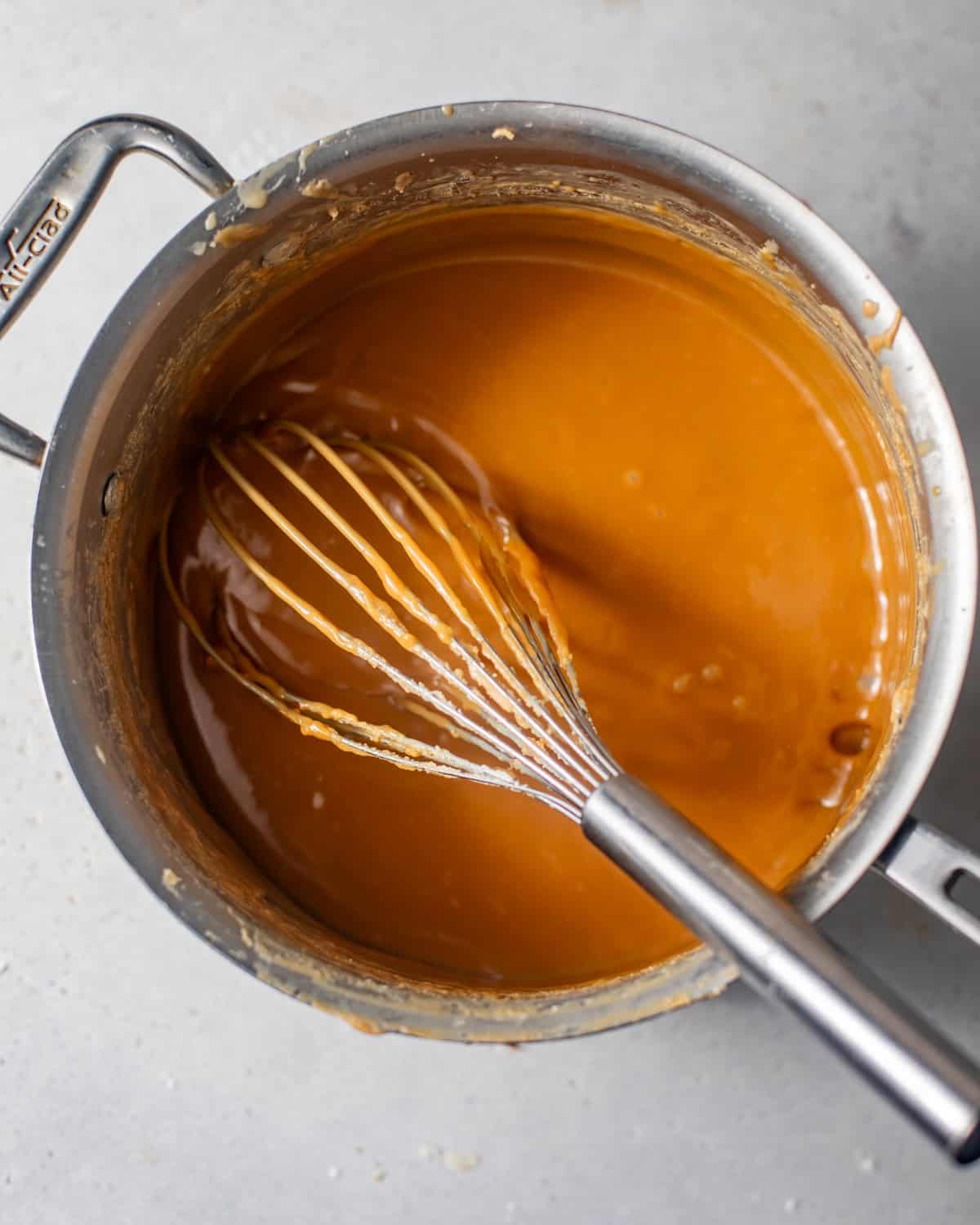 caramel frosting in a saucepan with a whisk.