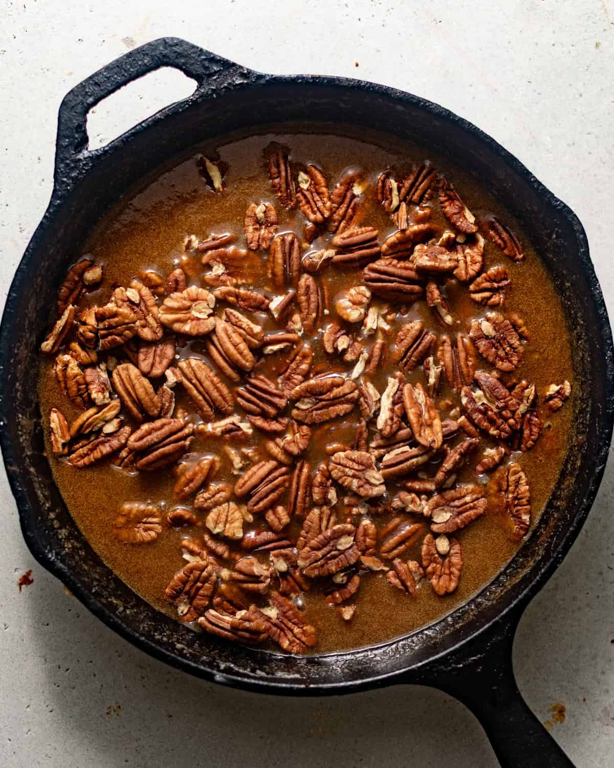 chopped pecans folded into the caramel sauce in a skillet to make the pecan pie filling.