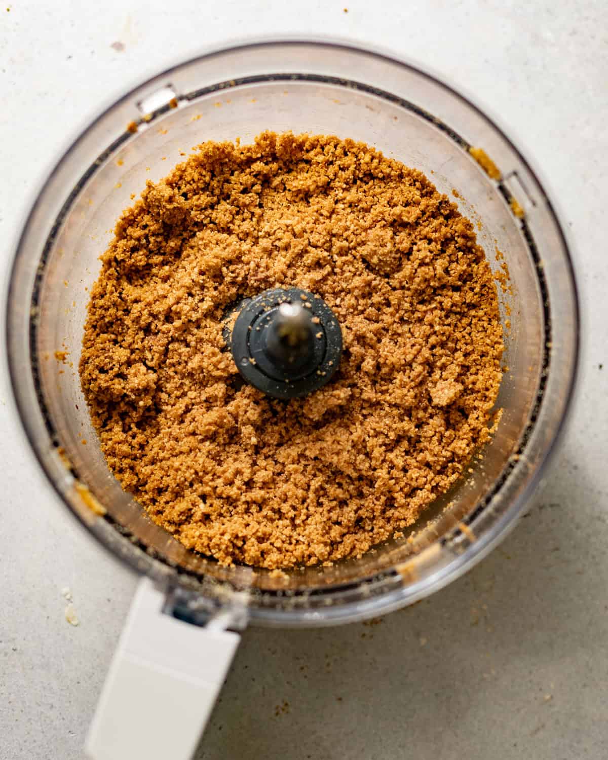 graham cracker crumbs in a food processor with pecans and browned butter.