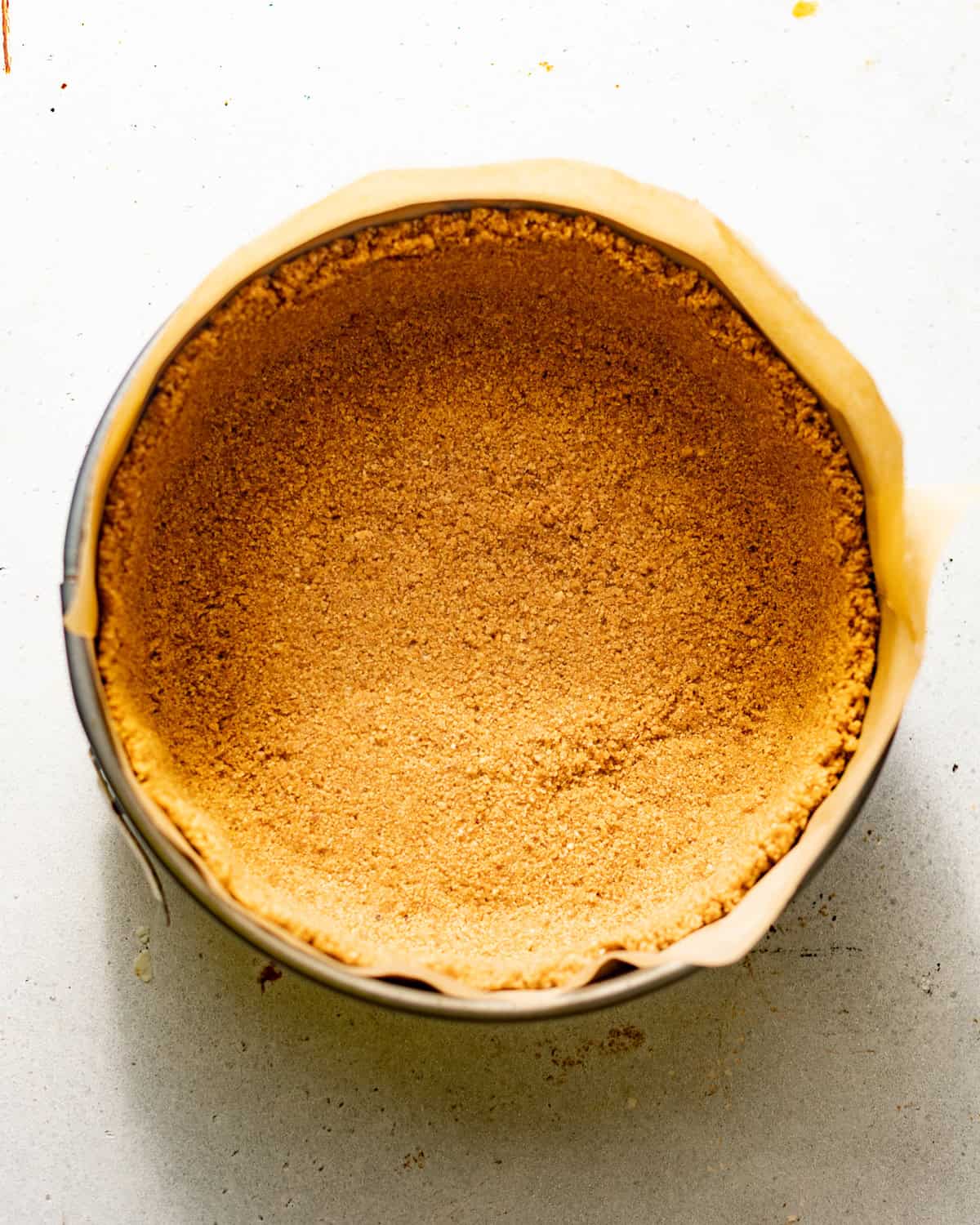 brown butter pecan graham cracker crust pressed into a parchment lined springform pan.