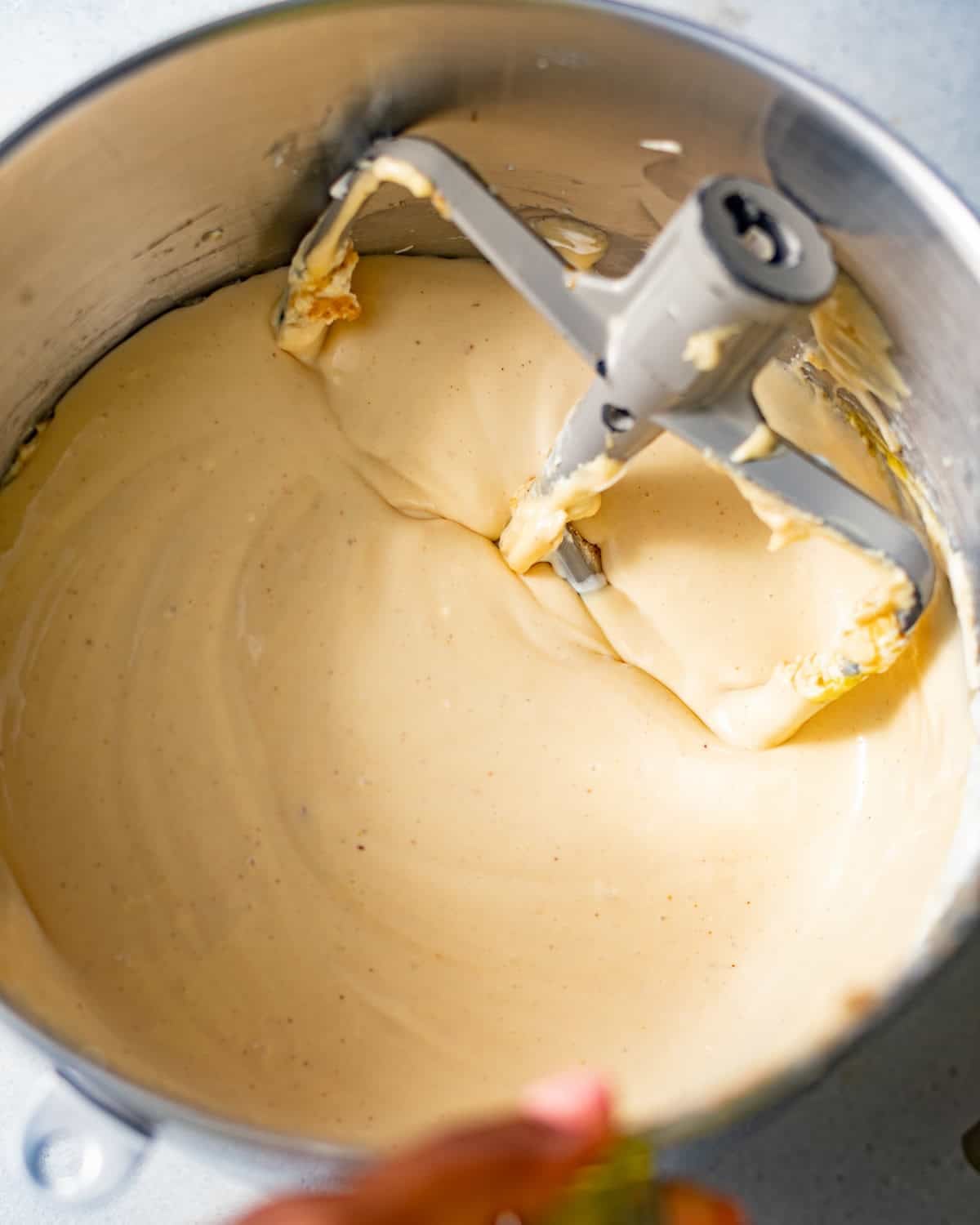 creamy pecan cheesecake batter in the bowl of a stand mixer with a paddle attachment.