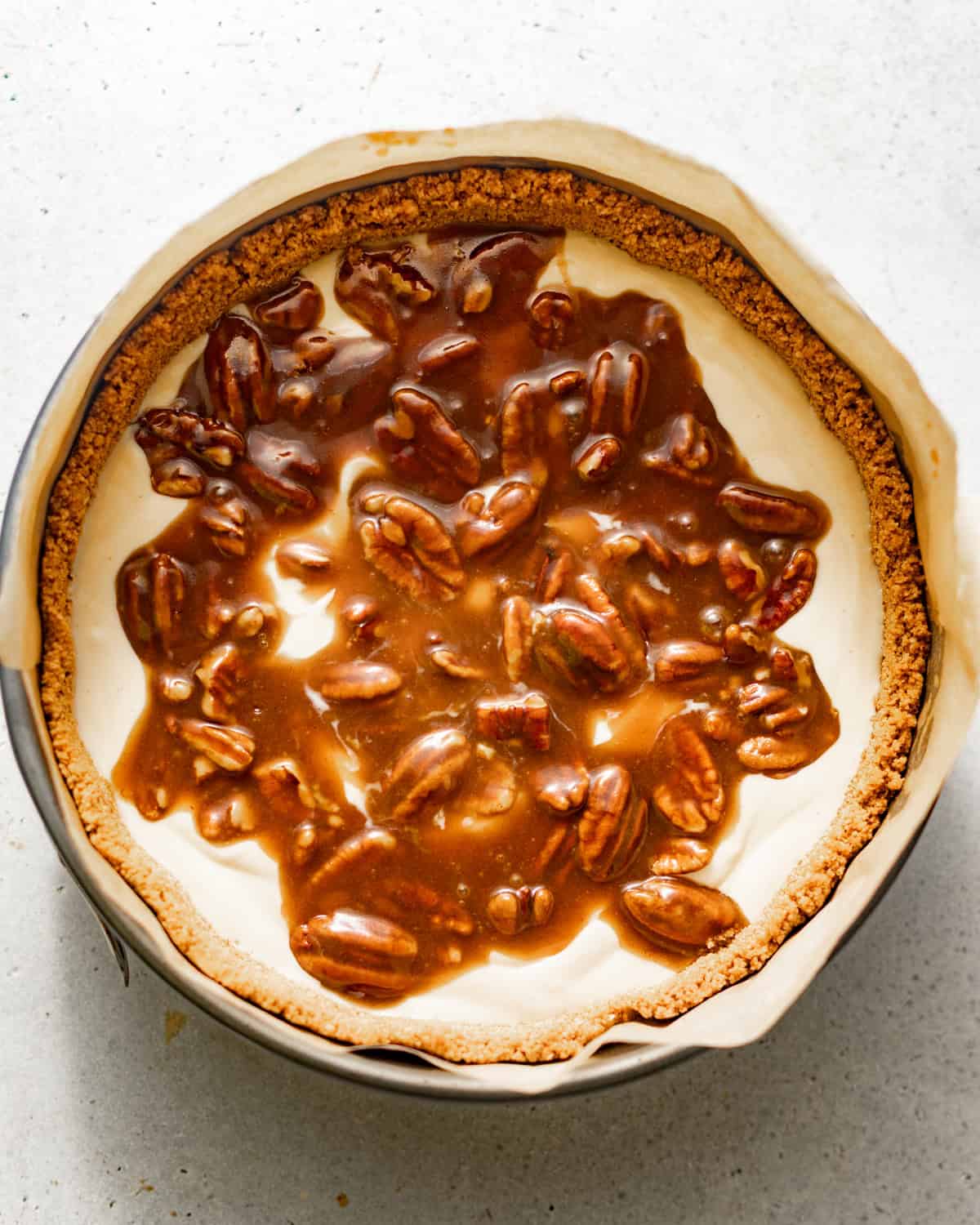 half of the cheesecake batter poured into the springform pan with half of the pecan pie filling in the middle.
