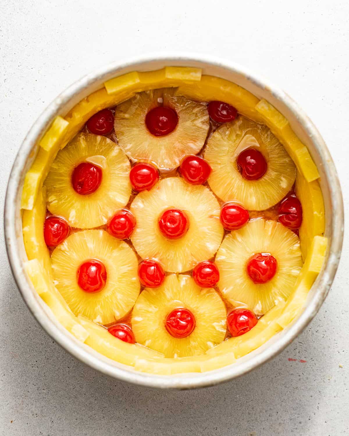 pineapple rings and maraschino cherries lined on the bottom of the cake pan to form the pineapple upside down cake topping.