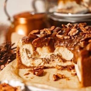 sliced pecan pie cheesecake on a serving plate topped with pecan pie filling.