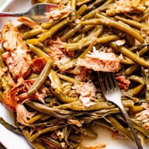 slow cooker green beans with smoked turkey on a serving plate with a serving fork.
