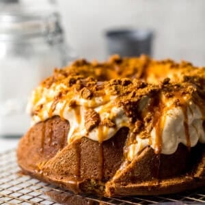 biscoff pound cake on a wire rack with glaze, caramel, and crushed cookies on top.